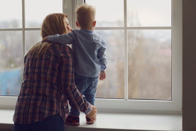 a mom and baby looks out a window