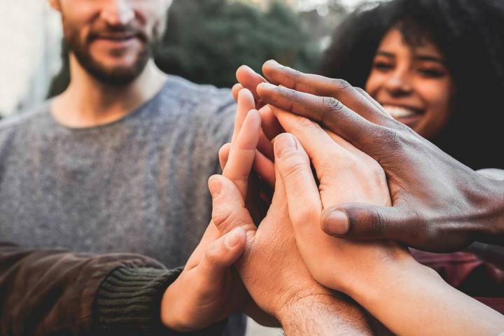 Young happy people stacking hands outdoor